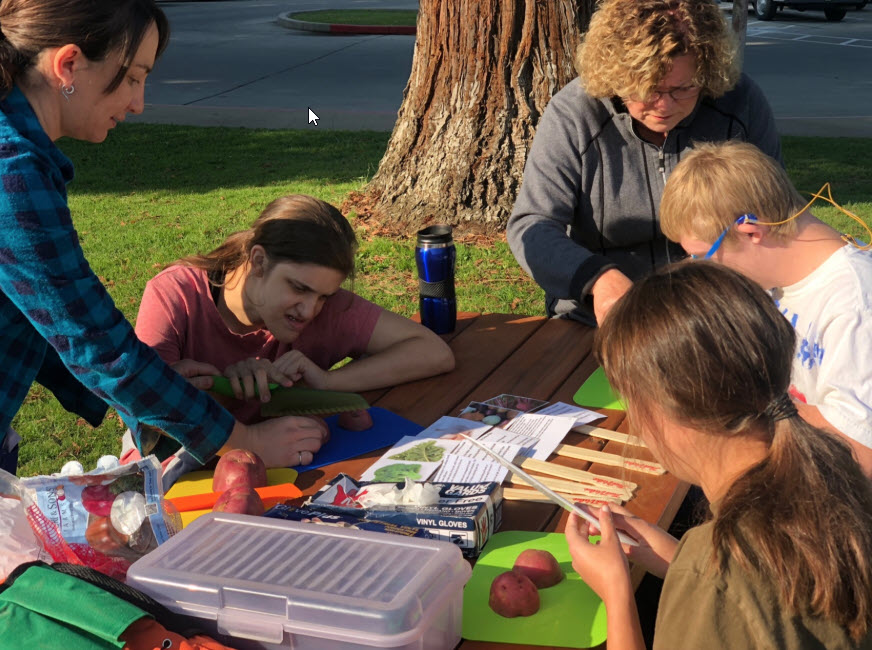 Students and staff working on a crafts project at a local park or playground area.