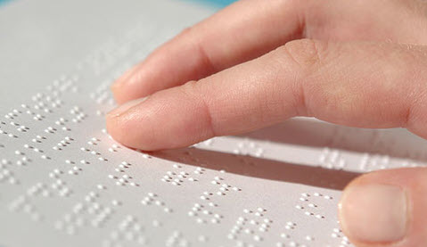 image of a hand moving over a Braille text page